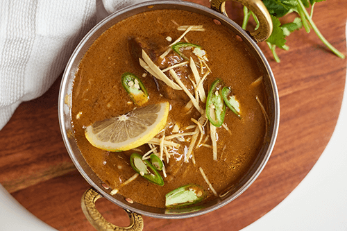 A bowl of curry on a wooden board.